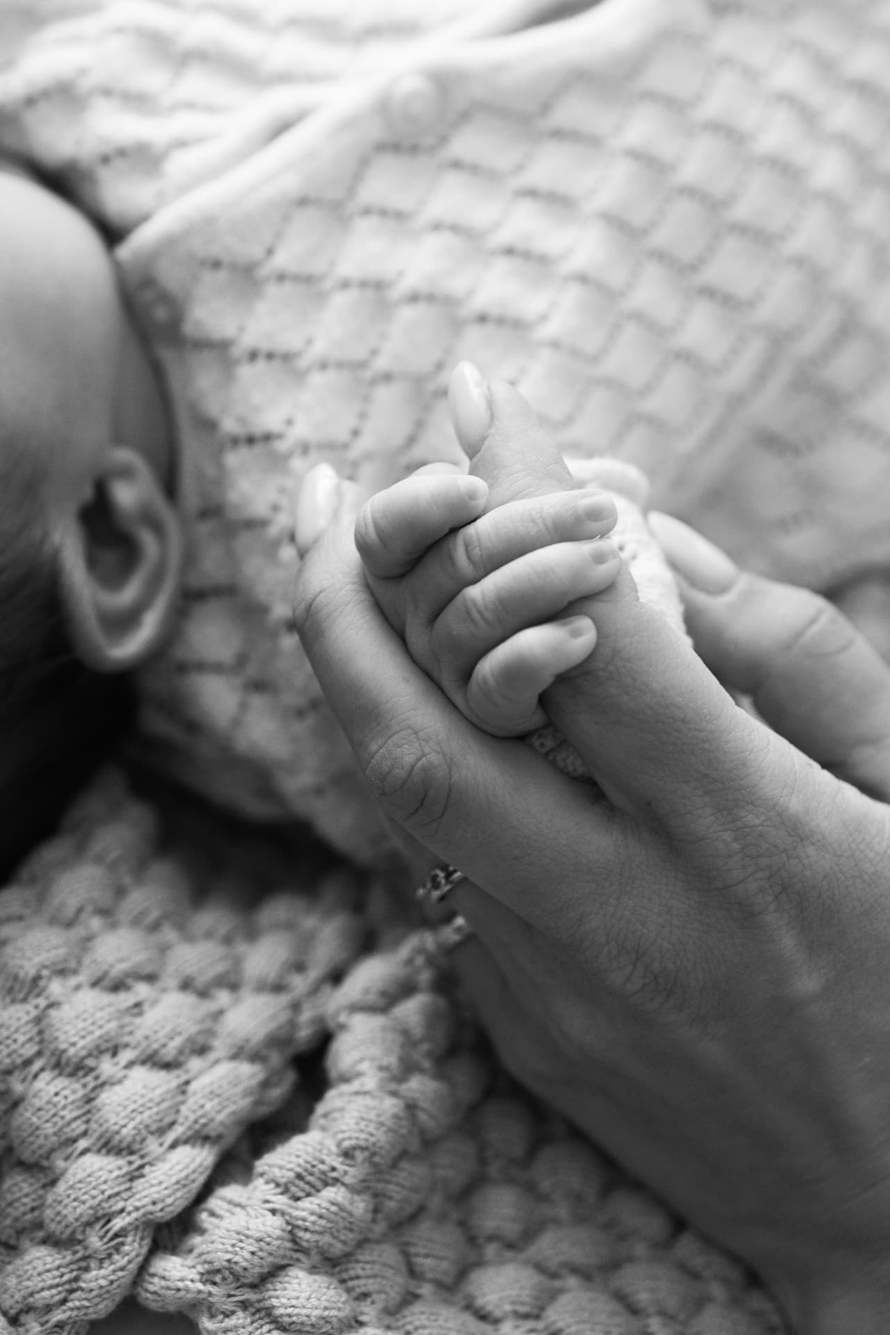 Oudere zus knuffelt newborn tijdens een fotoshoot thuis