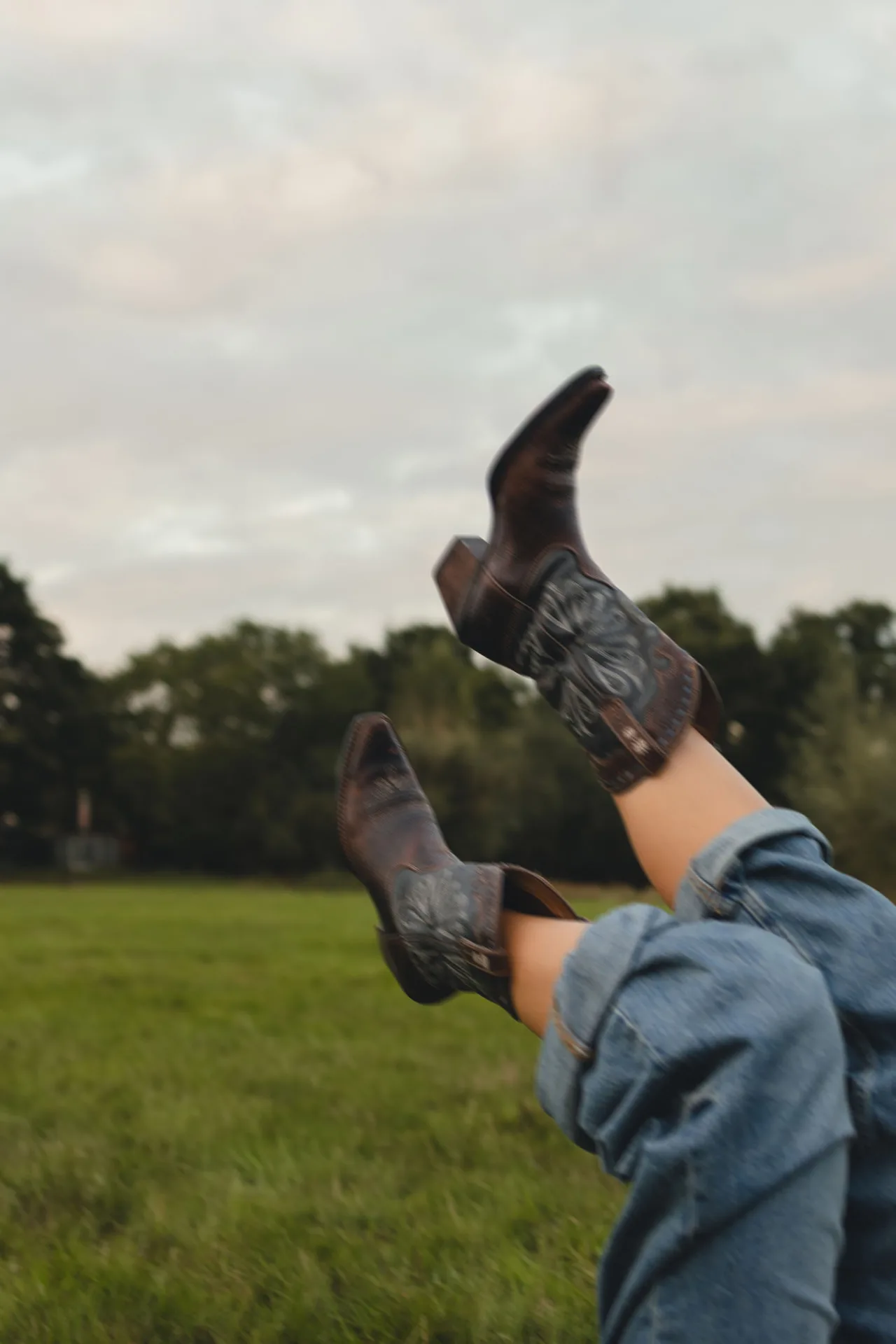 Speels detailbeeld van cowboylaarzen in een groene buitenomgeving